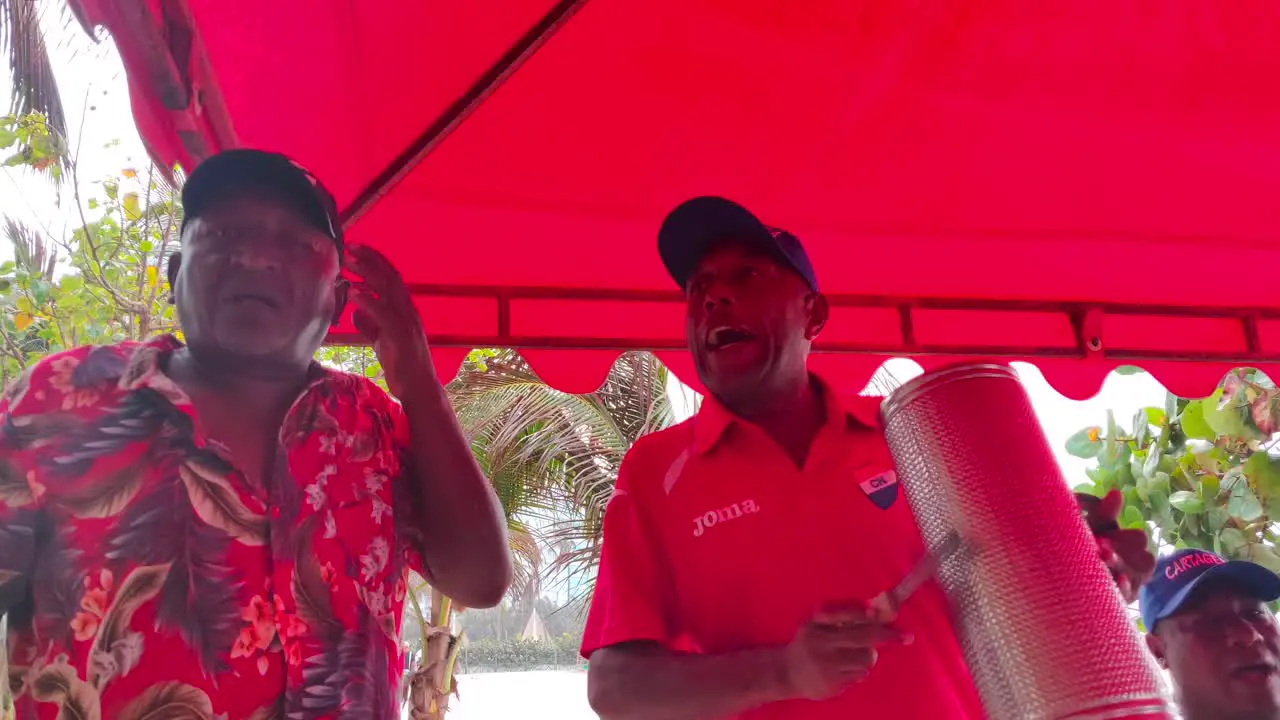 A man is singing along with his band who are playing the Guacharaca the caja and the accordion