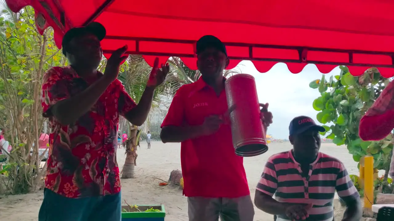 A band of Vallenato is playing Guacharaca accordion and caja while they sing and dance songs on a beach of Cartagena de Indias Colombia