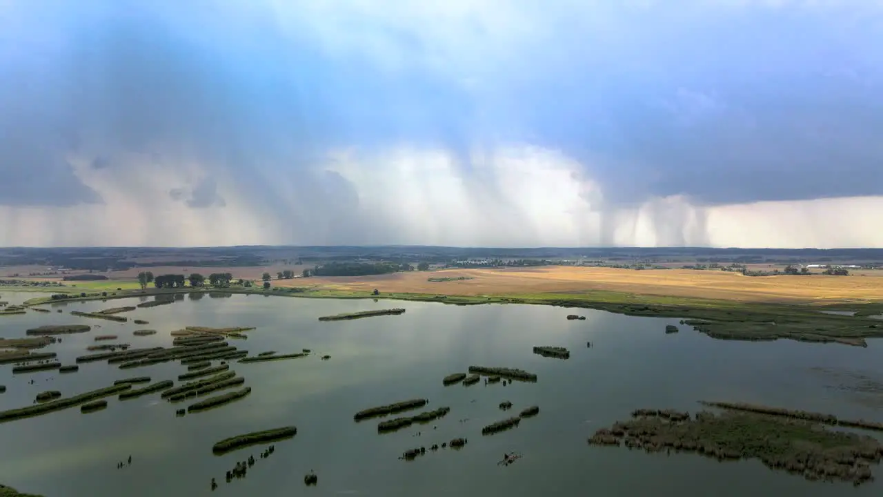 Aerial elevation shot of wetlands and vast farm field with distant storm