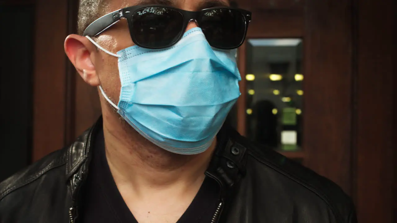 Man walks outside wearing covid-19 surgical mask and sunglasses