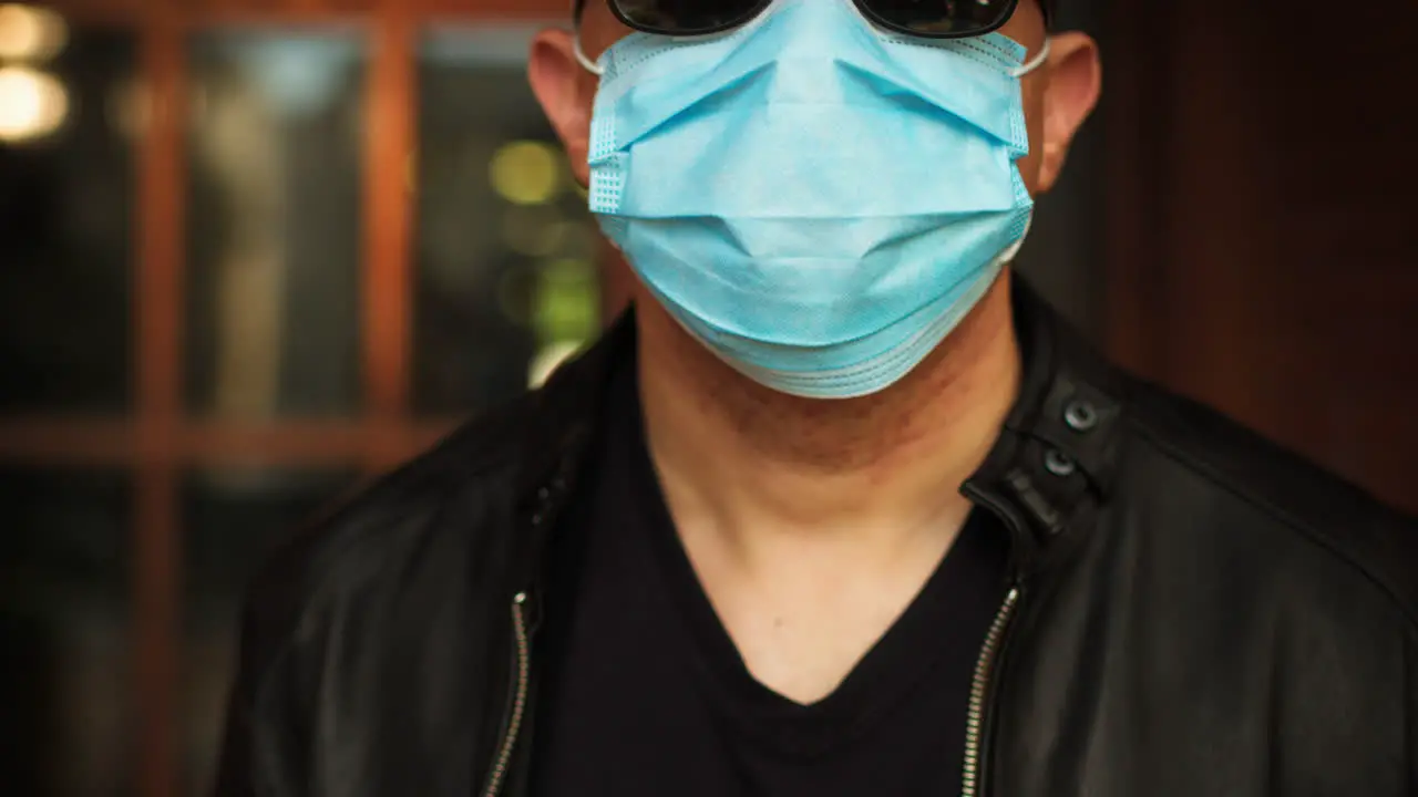 Man standing outside wearing a covid-19 surgical mask and sunglasses