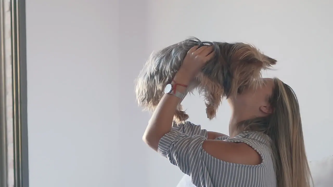 Woman Lifting Her Dog In The Air And Kissing It