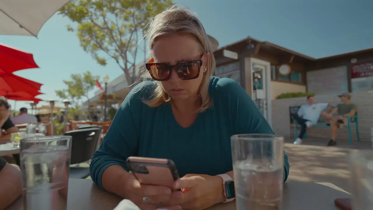 Caucasian woman playing on cell phone while outdoor dining