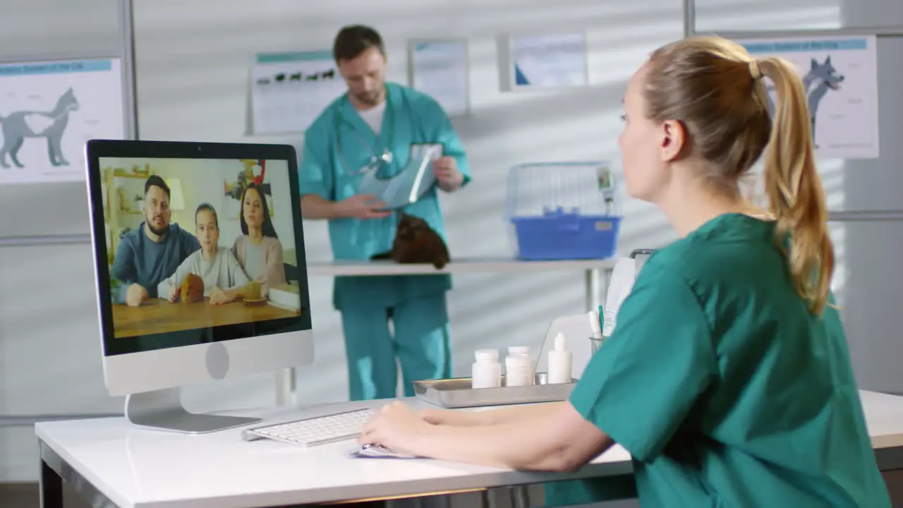 Female Veterinarian In Scrubs Giving Online Consultation Via Video Call And Talking To A Family With A Hamster