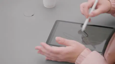 Close Up Shot of Woman Sitting at Outdoor Table Sketching On Tablet