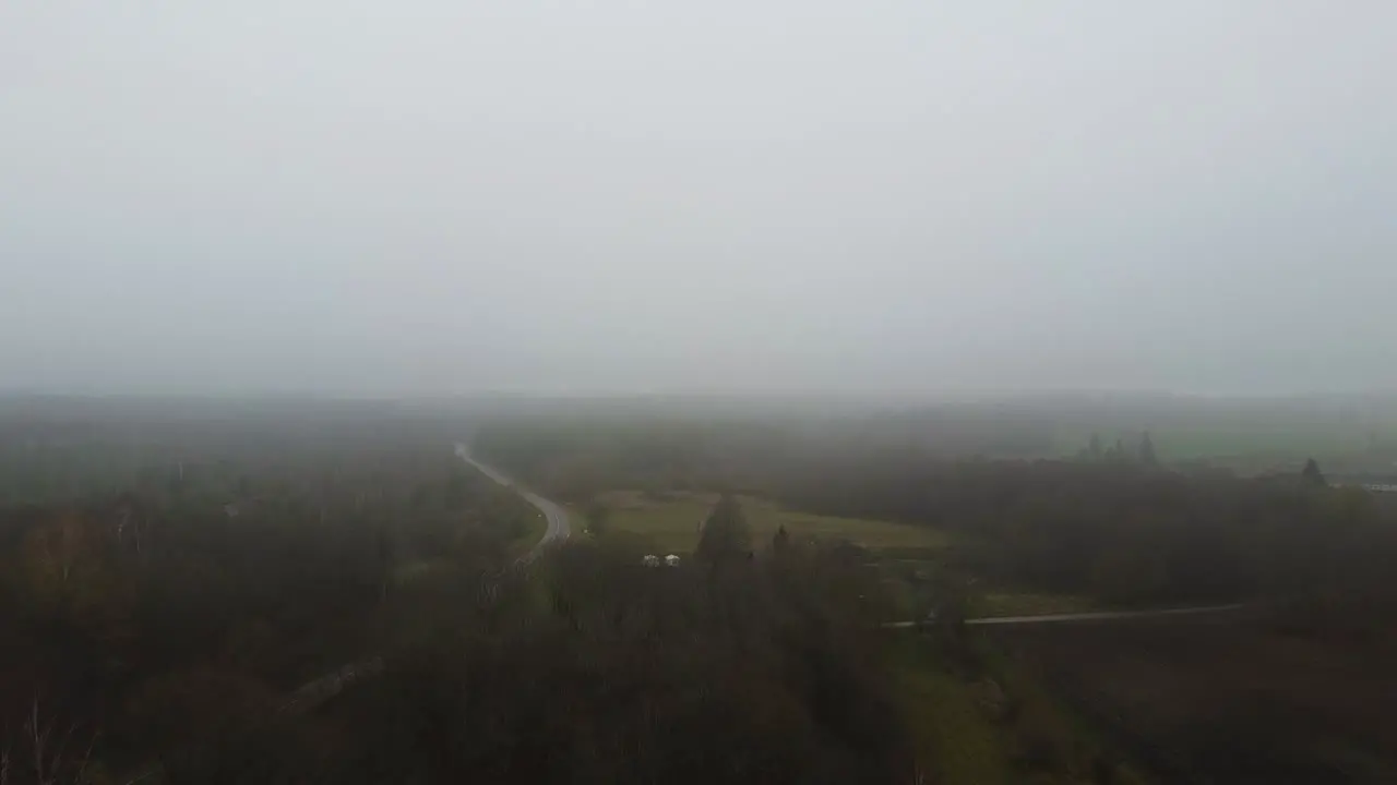 Aerial Flying through Dense Fog over Lithuanian agriculture fields and forest on a cold autumn day