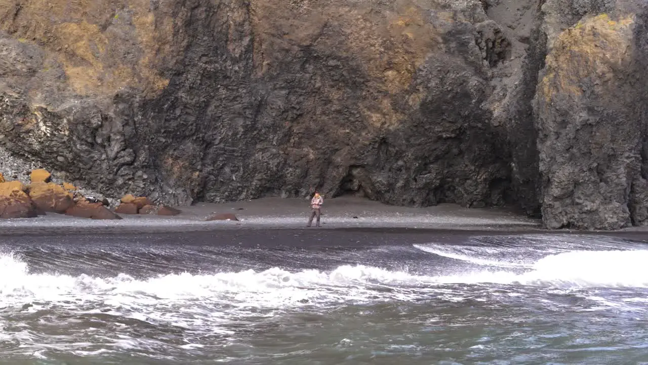 A lone man on the black sand beach in Iceland looks to the horizon