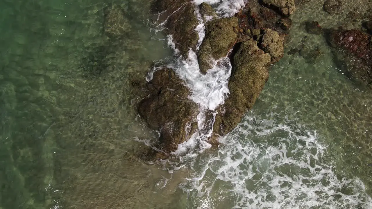 tropical waves break slowly over craggy rocks