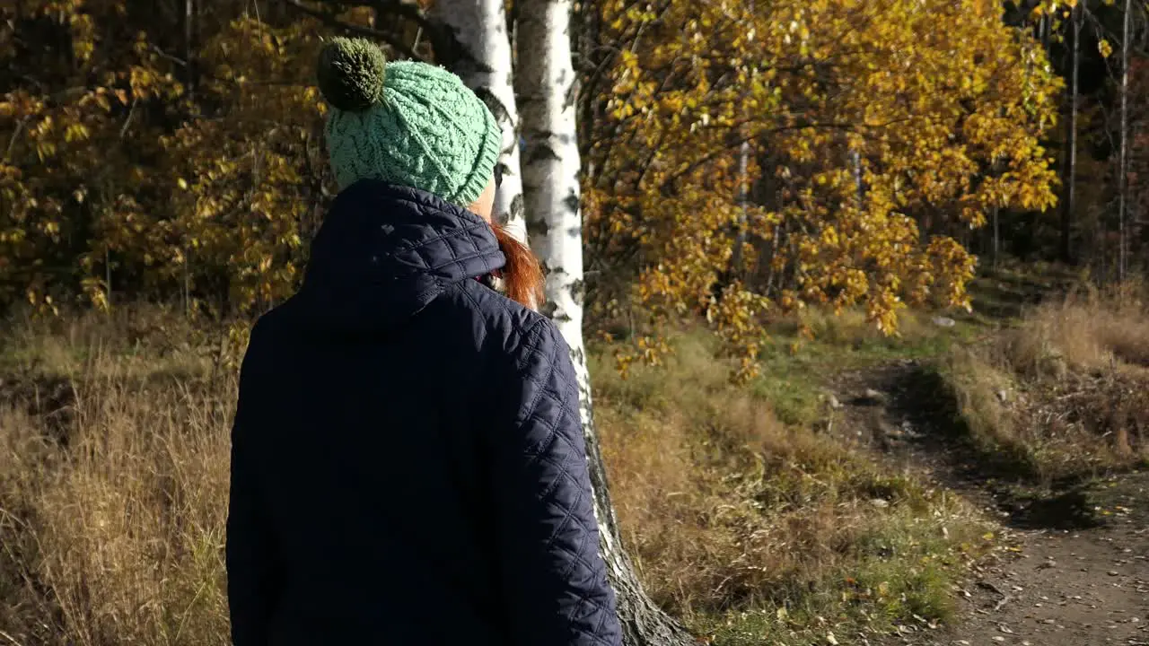 Woman walking forest path peacefully enjoying nature in fall