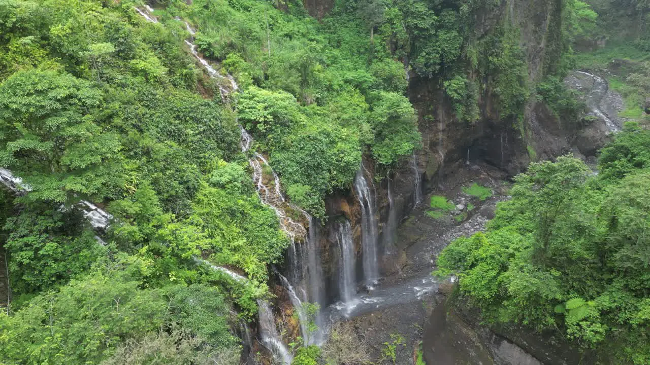 Aerial descends into deep misty lush waterfall canyon on Java IDN