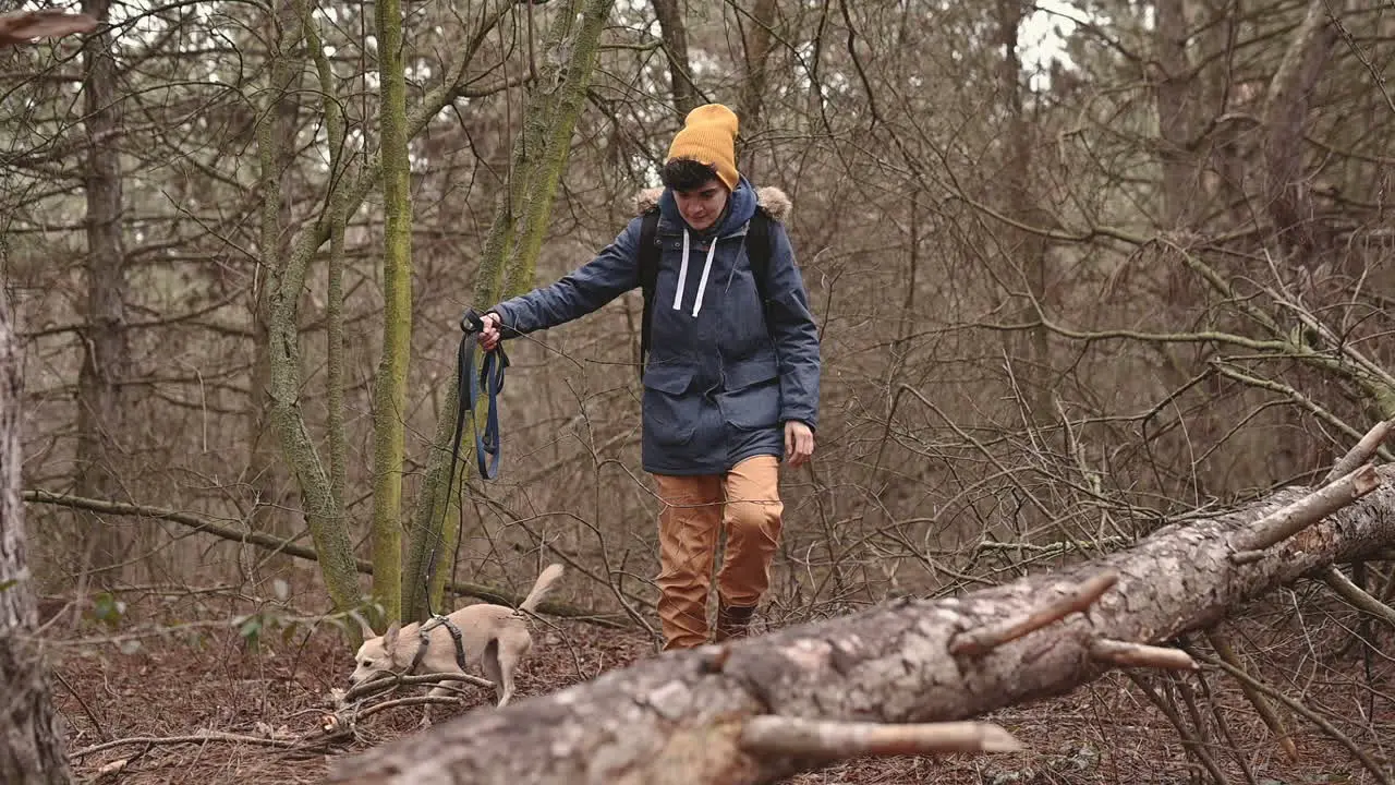 A Young Woman With Short Hair Takes A Walk With Her Dog Through The Forest