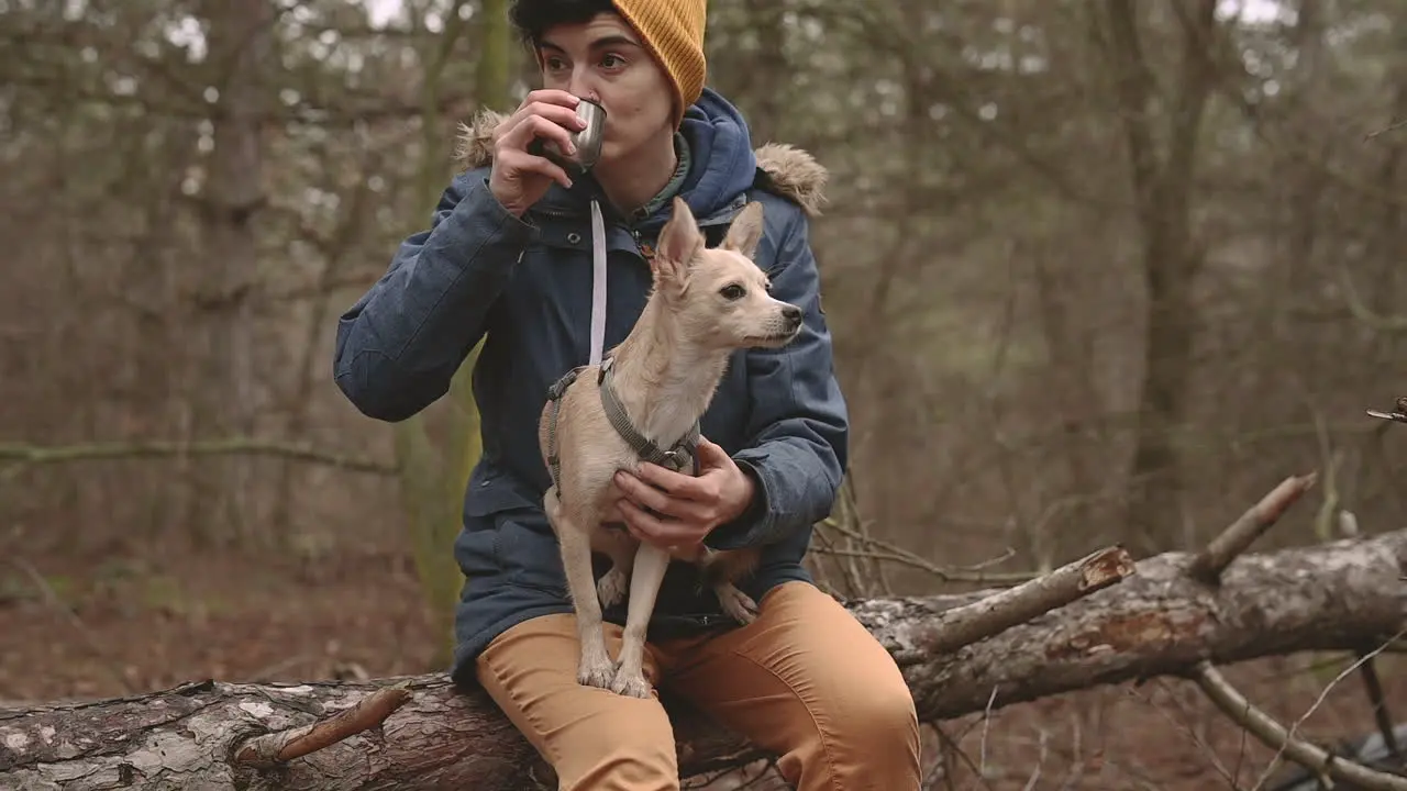 A Young Female With Short Hair Drinks A Hot Beverage In The Forest