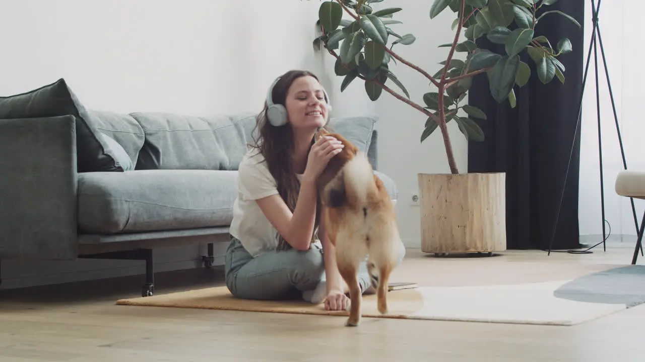 Young Woman Calls Her Dog To Feed Him While Working On Her Laptop At Home