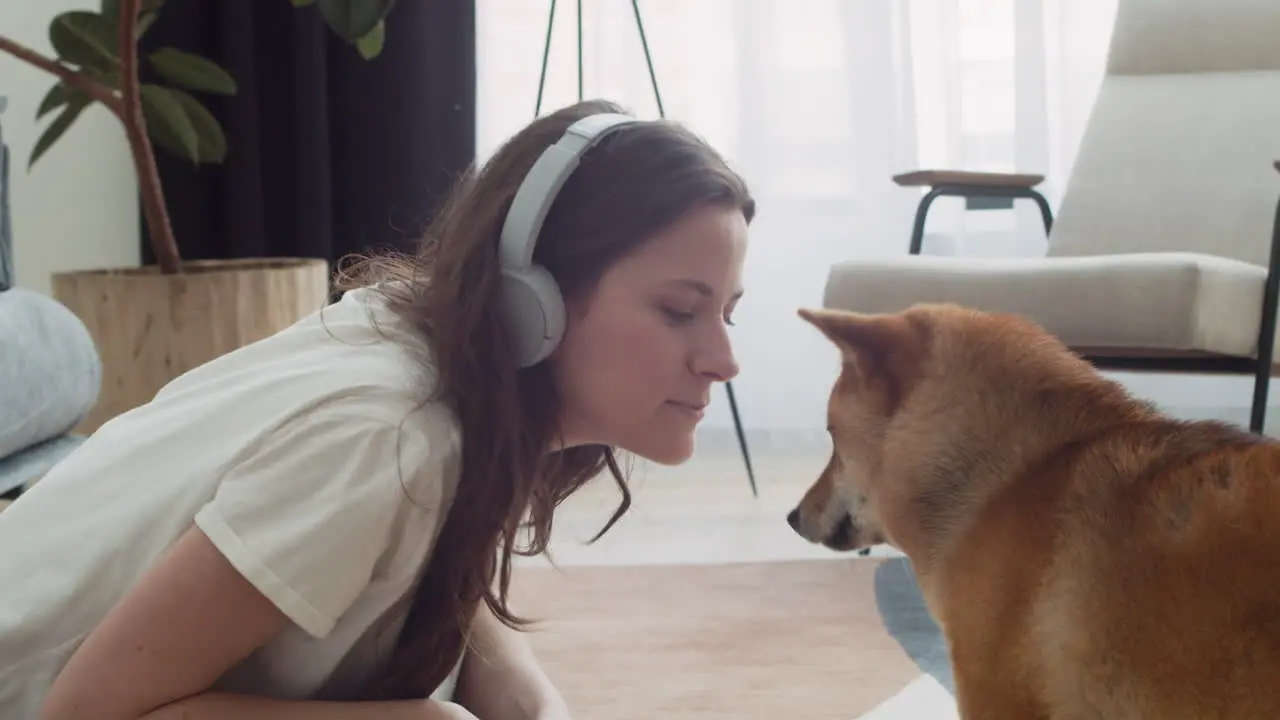 Pretty Girl Feeds And Pets Her Dog While Working On Her Laptop At Home 1