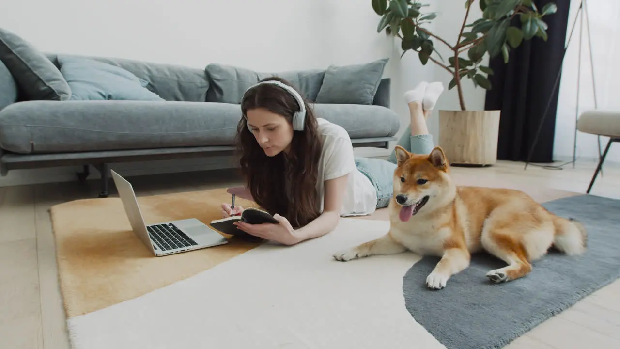 Young Woman Working On Her Laptop At Home Next To Her Dog 2