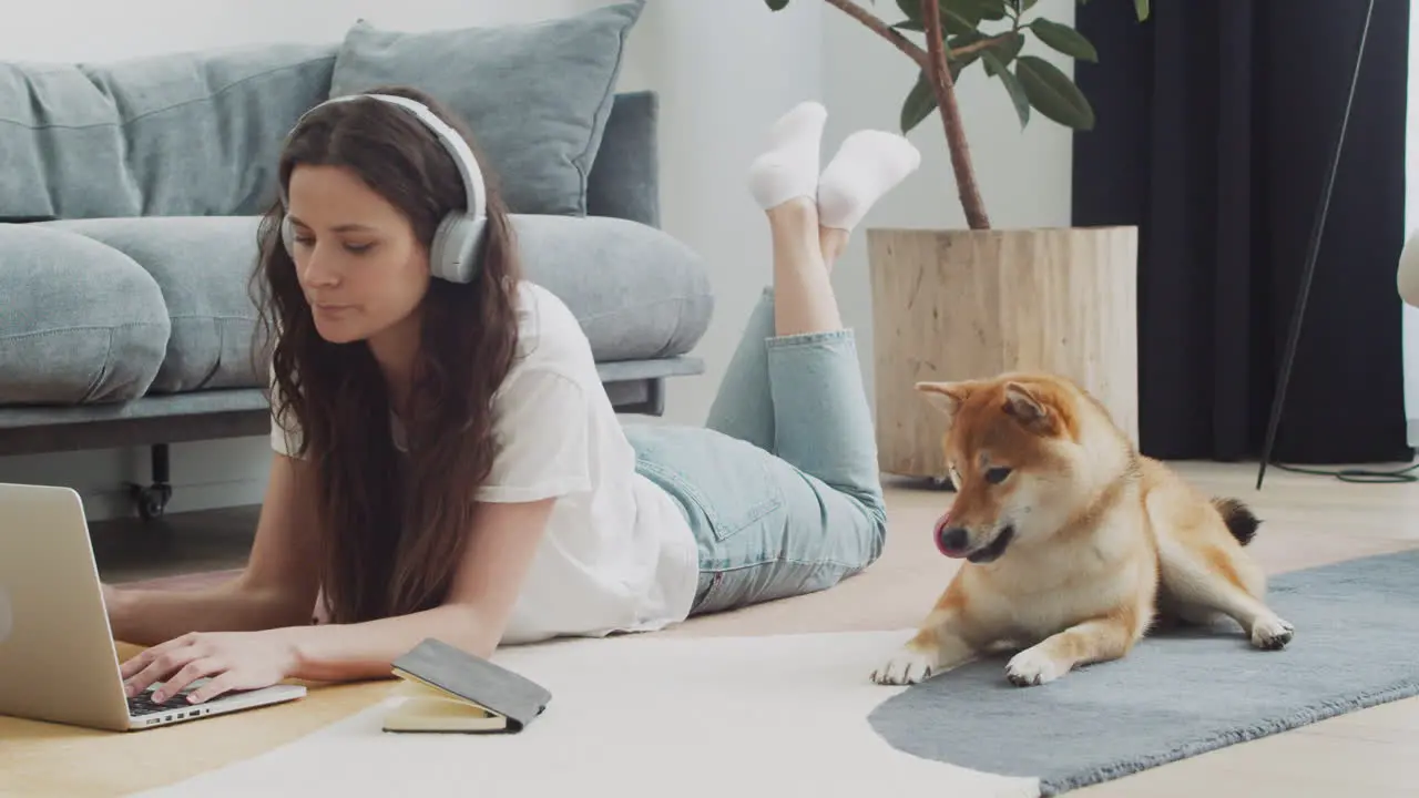 Young Woman Working On Her Laptop At Home Next To Her Dog 3