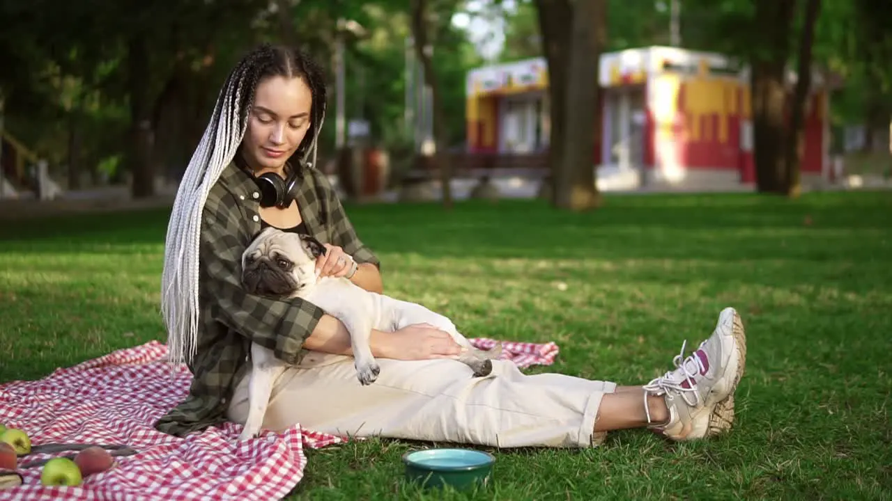 Girl With Dreadlocks Sitting On Plaid On Lawn In A Park