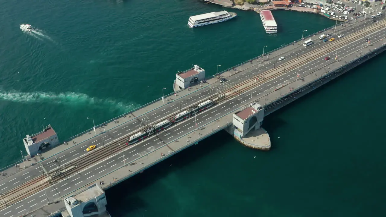 Public Transport Tram Train passing Galata Bridge over Bosphorus in Istanbul with Boats on water Scenic Aerial low angle follow shot