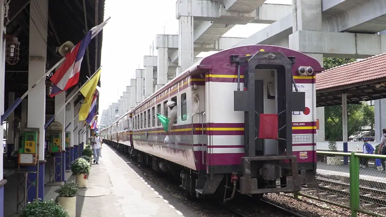 Conductor putting a green flag out of the train in Bangkok