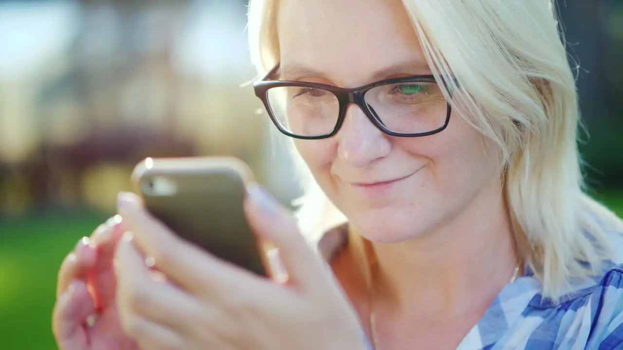 Portrait Of A Young Woman Wearing Glasses Enjoying A Smartphone In The Park Beautiful Sun Glare 4k S