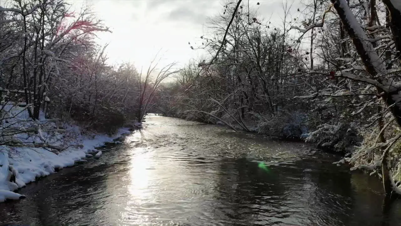 Aerial sunrise shot of creek in winter forest in Michigan USA