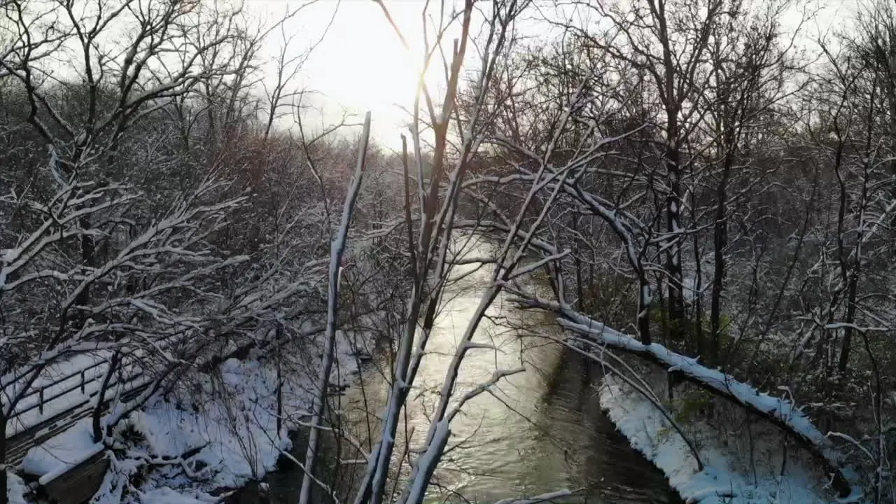 Rising aerial shot over wintry creek and forest in Michigan USA