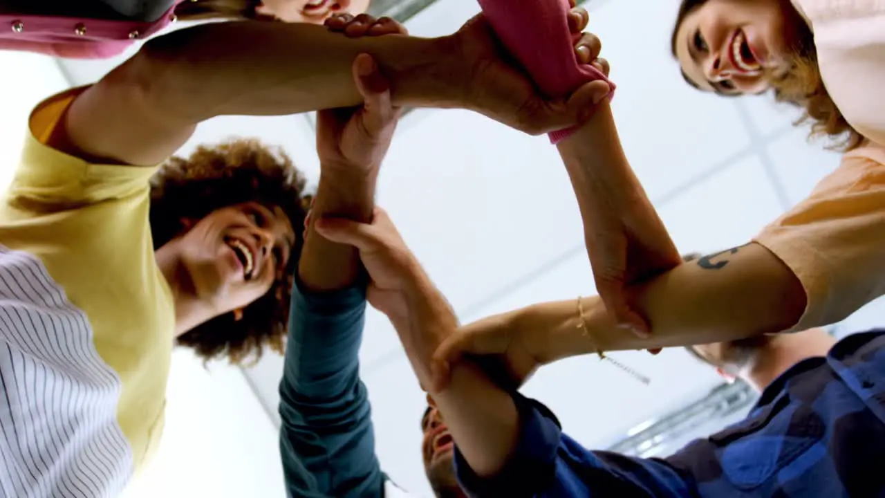 Team of smiling graphic designers forming hand stack