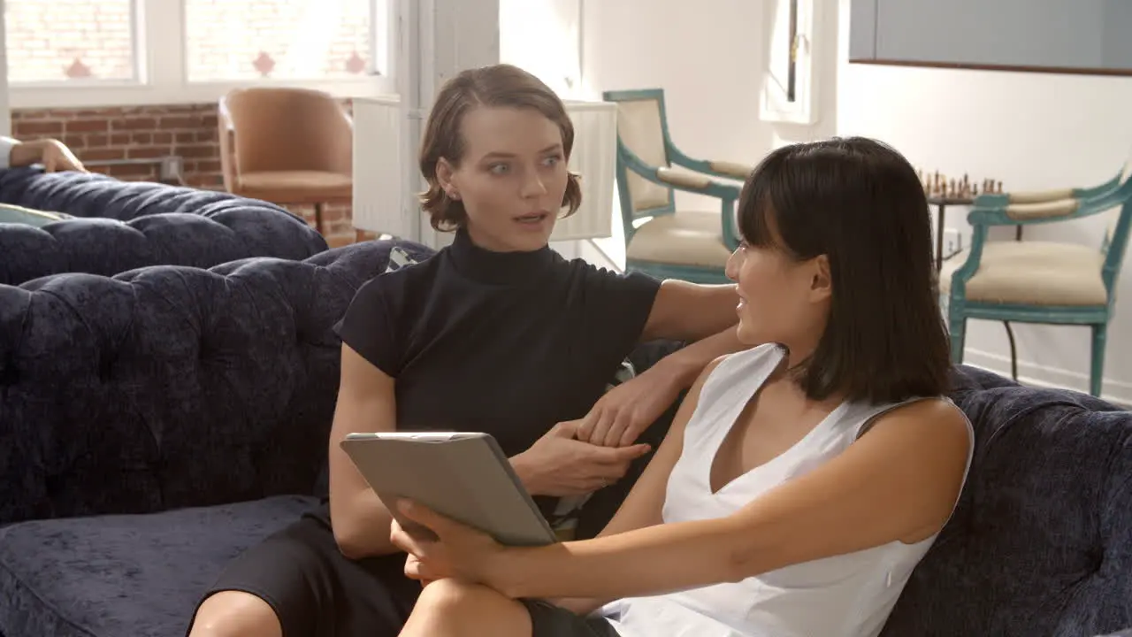 Businesswomen Working On Sofas In Relaxation Area Of Office