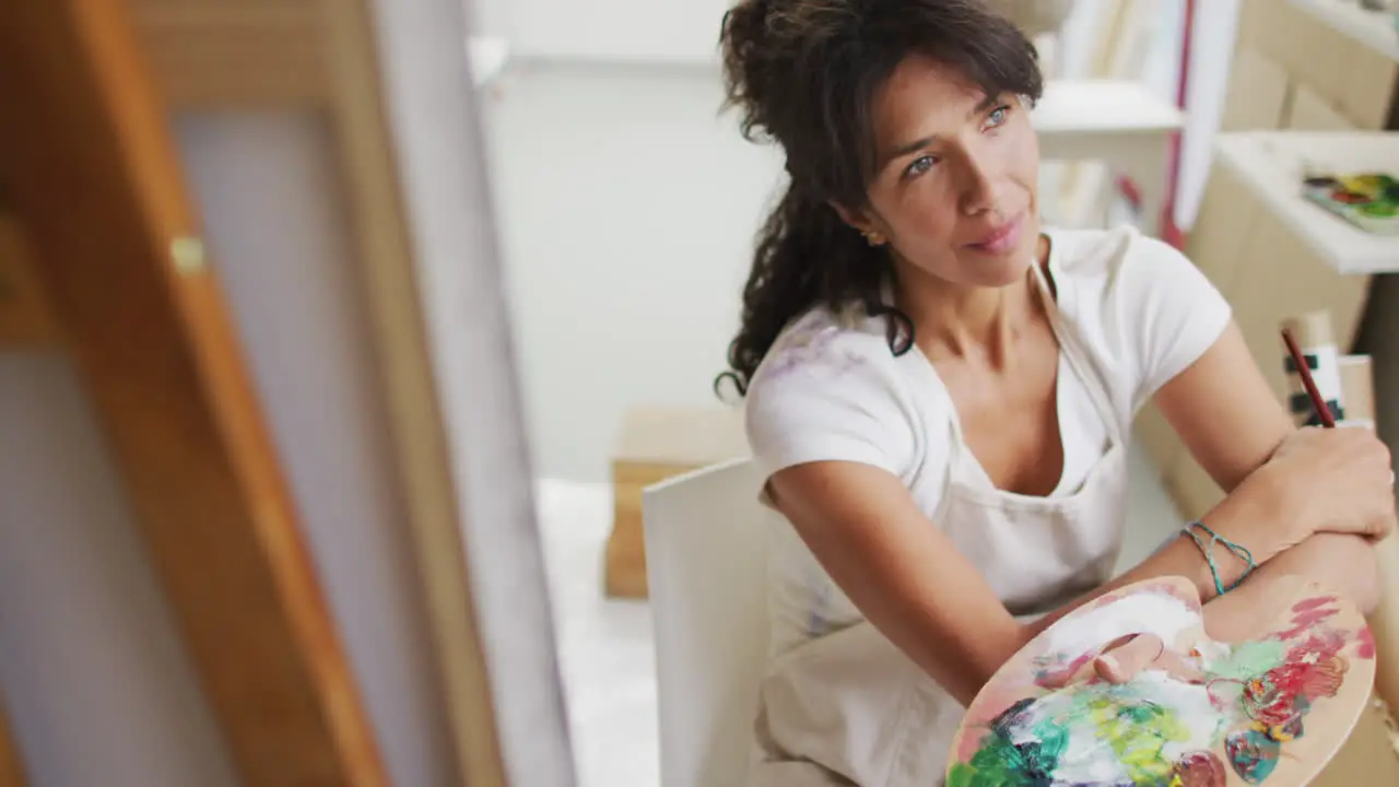 Biracial woman paints in a bright studio