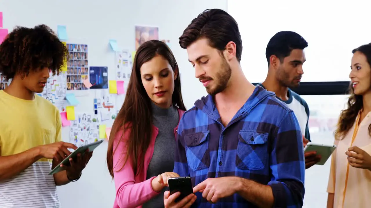 Smiling graphic designers discussing over digital tablet and mobile phone during meeting