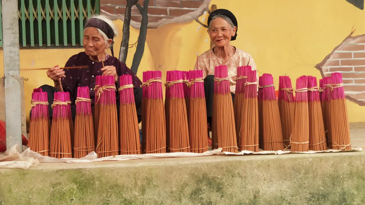 Two vietnamese elders sell incense for religious ceremonies on the street market