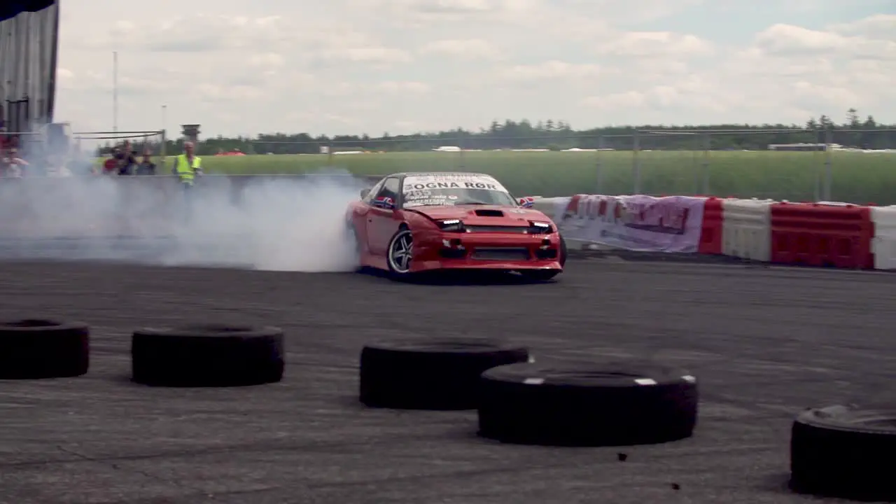 Red Nissan 240SX drifting on a drift track in super slow-motion with lots of smoke from the tyres in a close-up shot