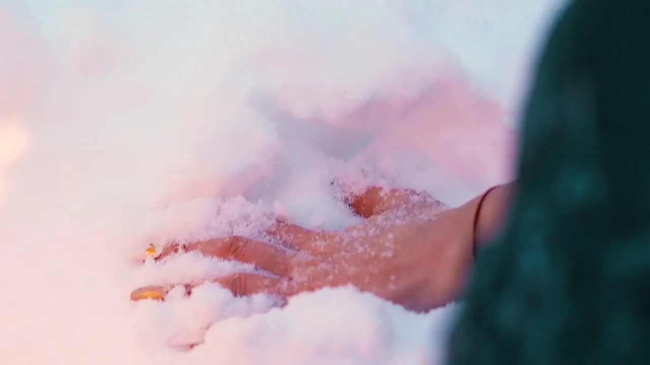 woman hand with manicure dipped in snow near burning fire