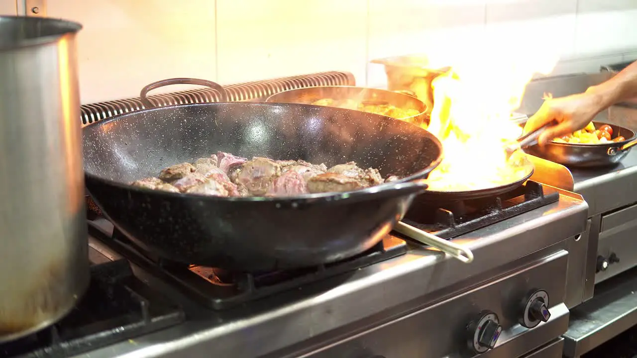 Close-up of a person cooking in a frying pan as a large flame comes out on the stove