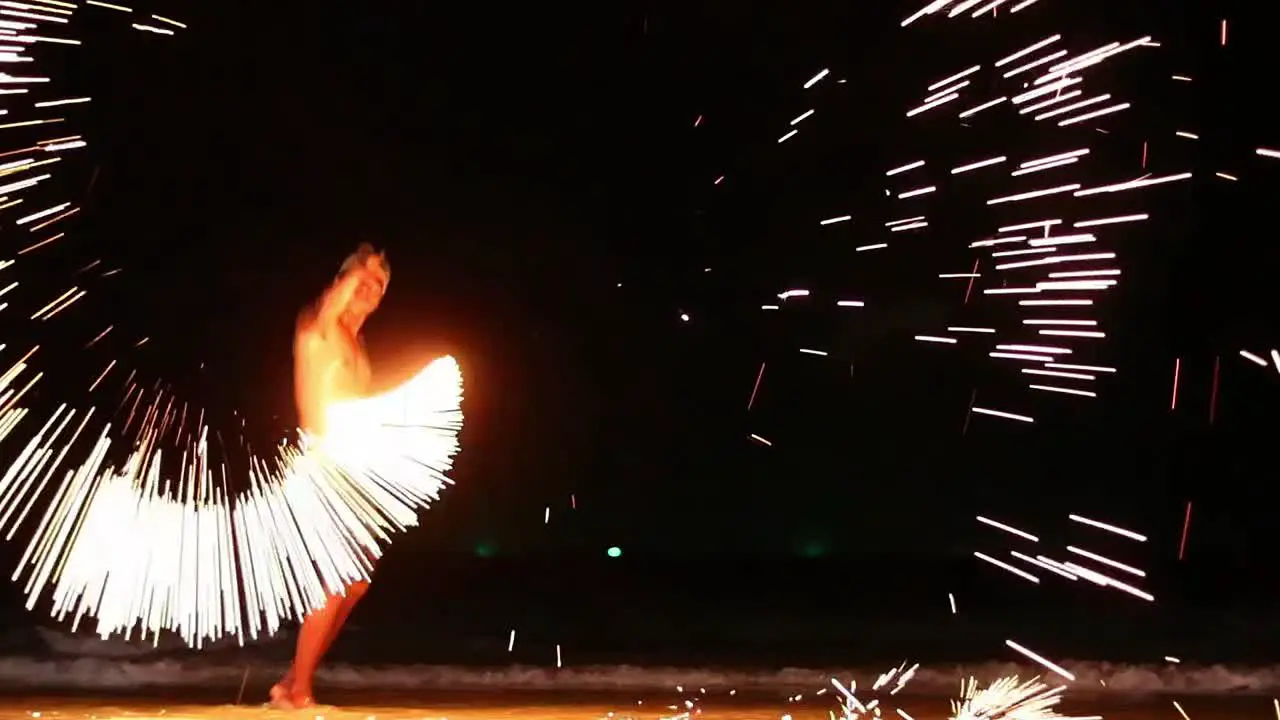 A thai man dances with a steel wool and chains in a fireshow performance until he creates a countless amount of sparks to entertain tourists at the beach of Samet Island Thailand