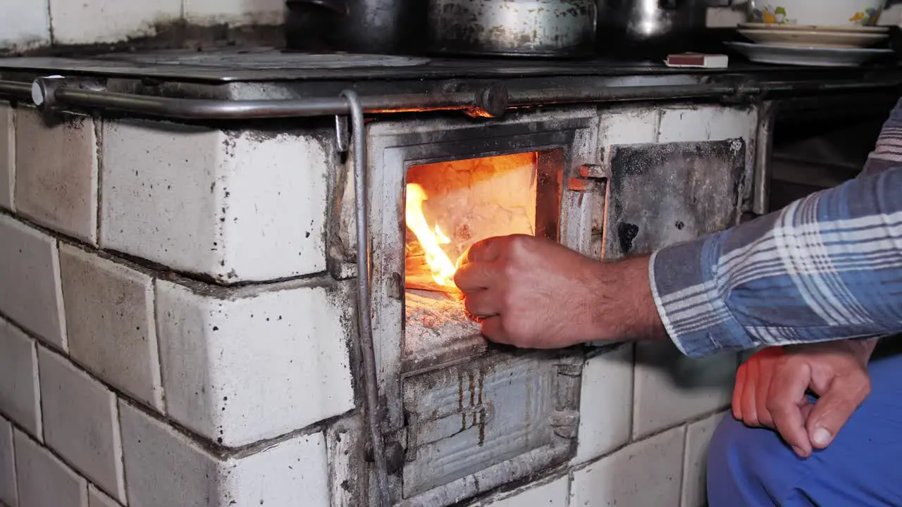 Man lights a wood in an old rustic kitchen stove with a match