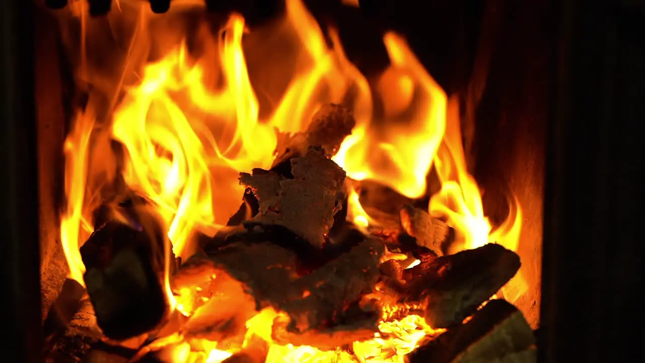 Ember and firewood in flames in stove static closeup view on yellow blaze