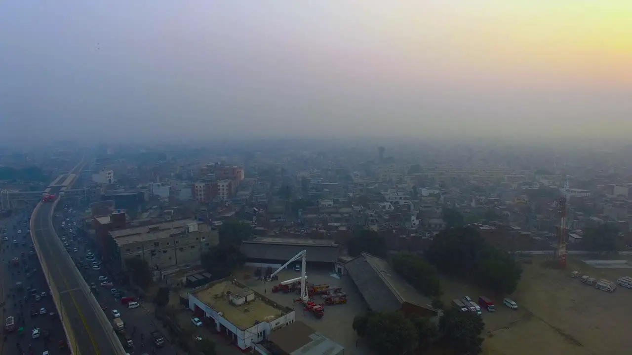 Aerial flight over the urban city Bombay India Top view crossing a metro bus bridge and a road two metro buses on its bridge passing a fire rescue center top view