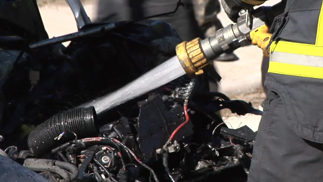 Firefighters Extinguish a Burning Car With Hoses