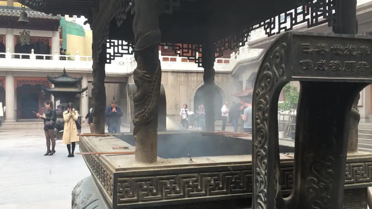 People praying with burning incenses and candles at Yuyuan Garden in Shanghai China with a lot of smoke