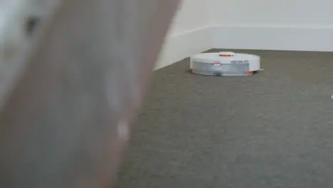 Long Shot of an Automatic Robotic Vacuum Cleaner Cleaning Carpet