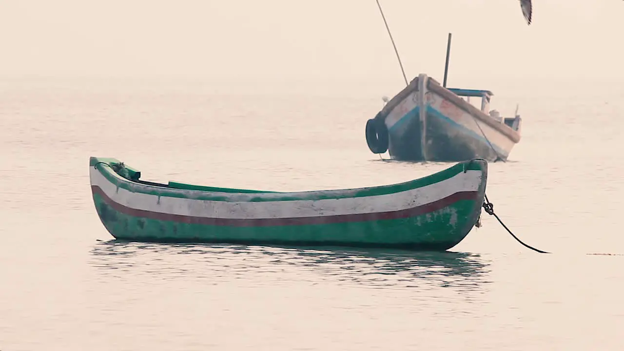 Small wooden boat bobs and swings on calm waves in sea without people or sailor a small boat near a beach shore without a people in calm waves background video mov in full HD