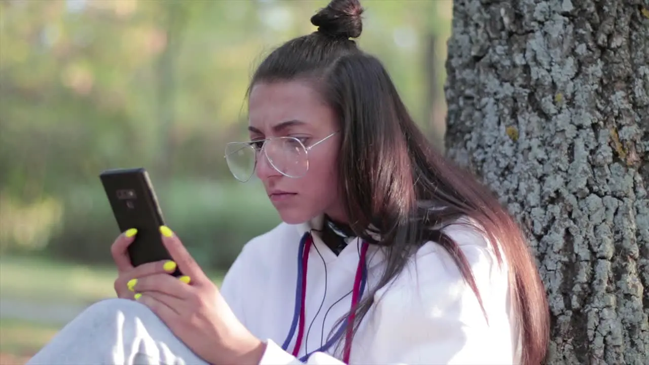 Beautiful girl in a park watching something surprising on her phone