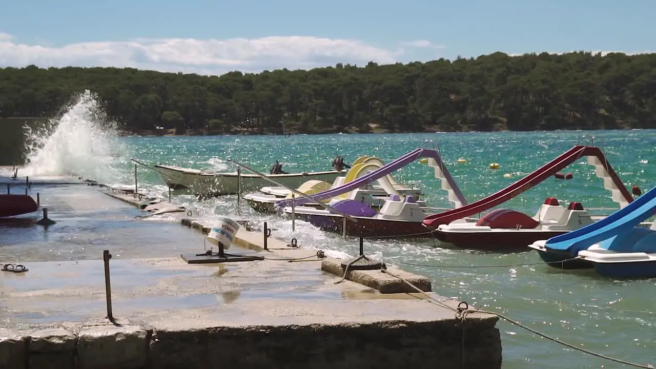 pedal boats swaying in waves at a wharf with splashing water in slow motion