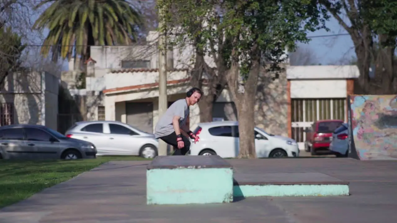 An adult man wearing headphones practicing tricks on a skateboard