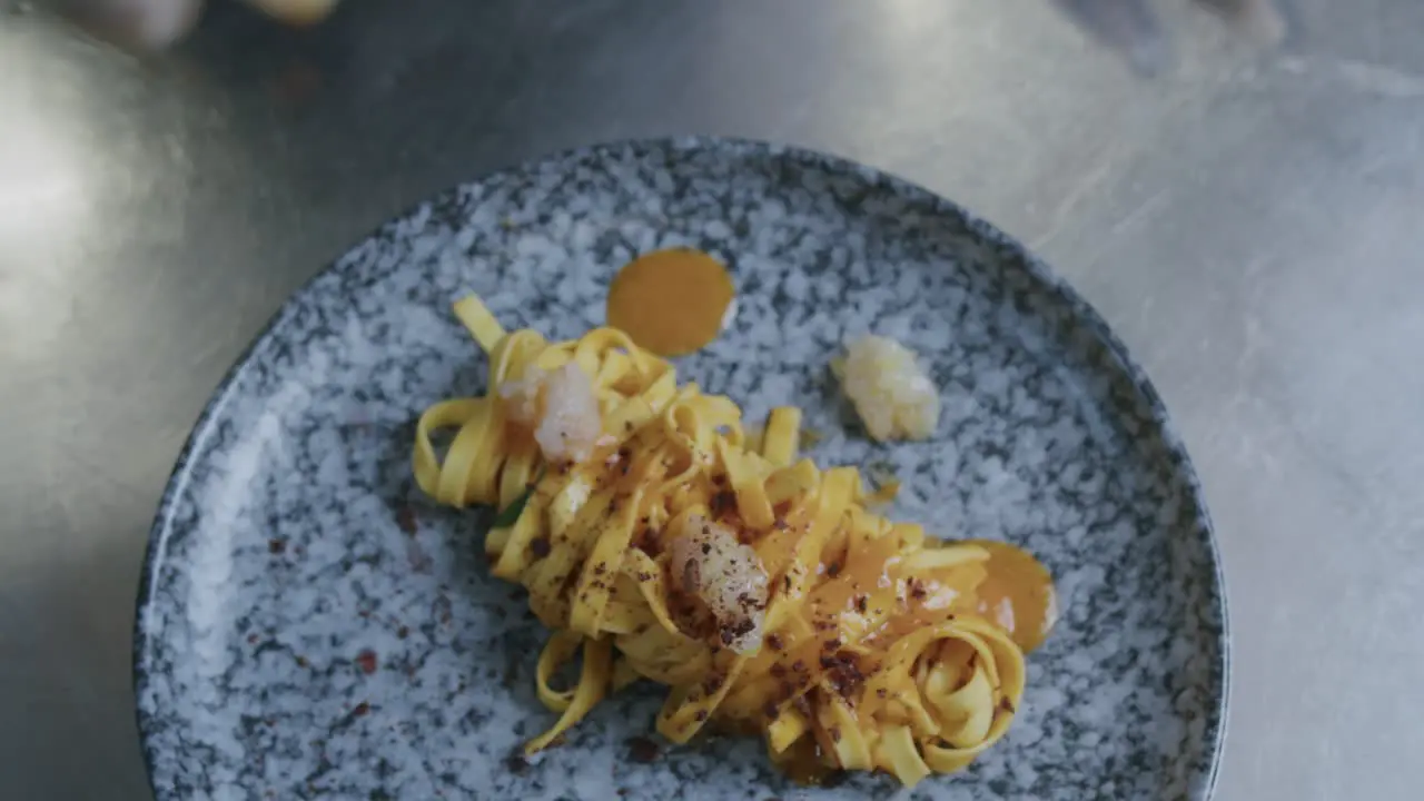 A professional chef in Italy is prepairing a plate of pasta and scampi in his kitchen 02