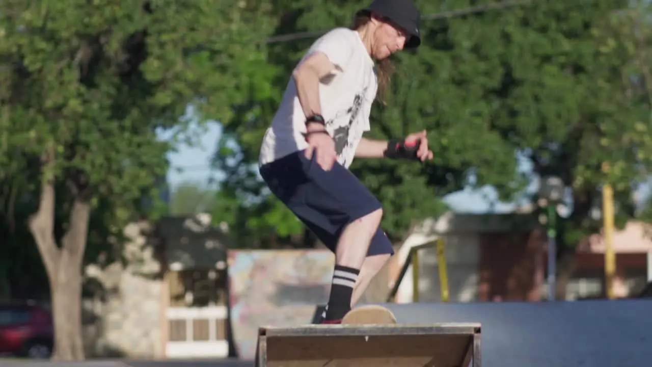 A redhead man jumps off a quarter pipe ramp on his skateboard