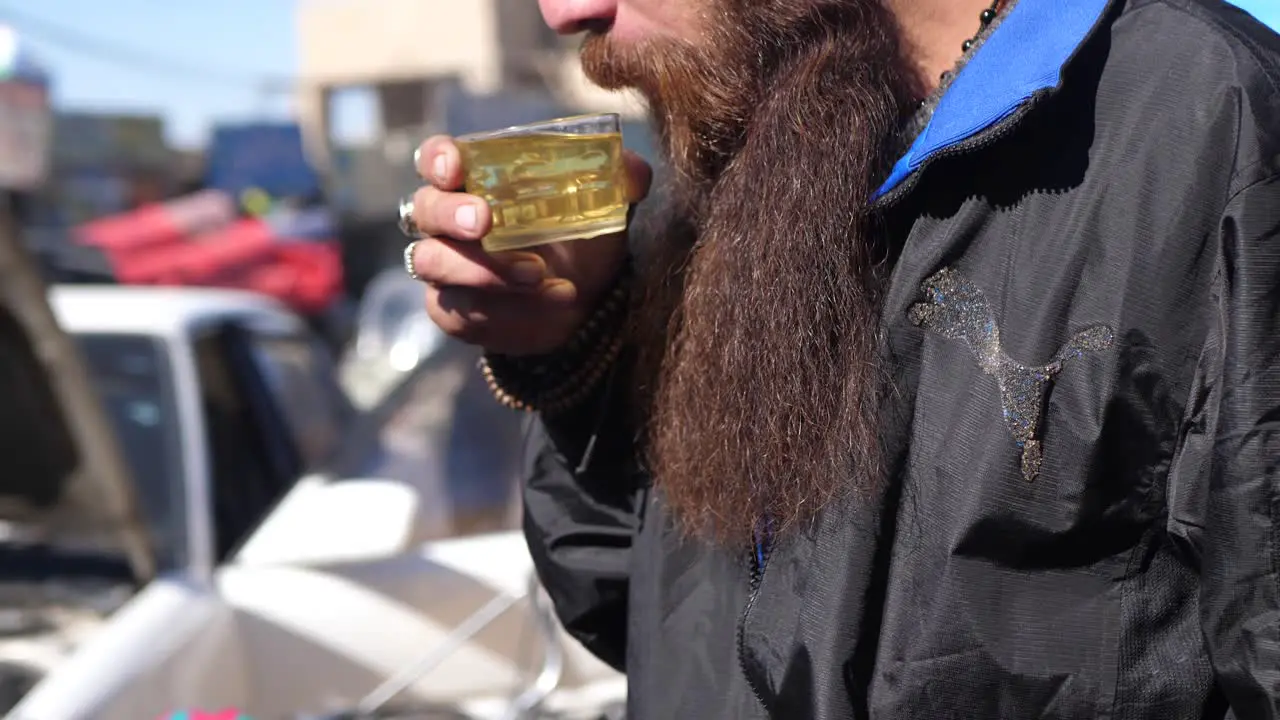 Pakistani Male With Long Beard Slowing Lift Cup Of Hot Beverage To Drink In Street In Quetta