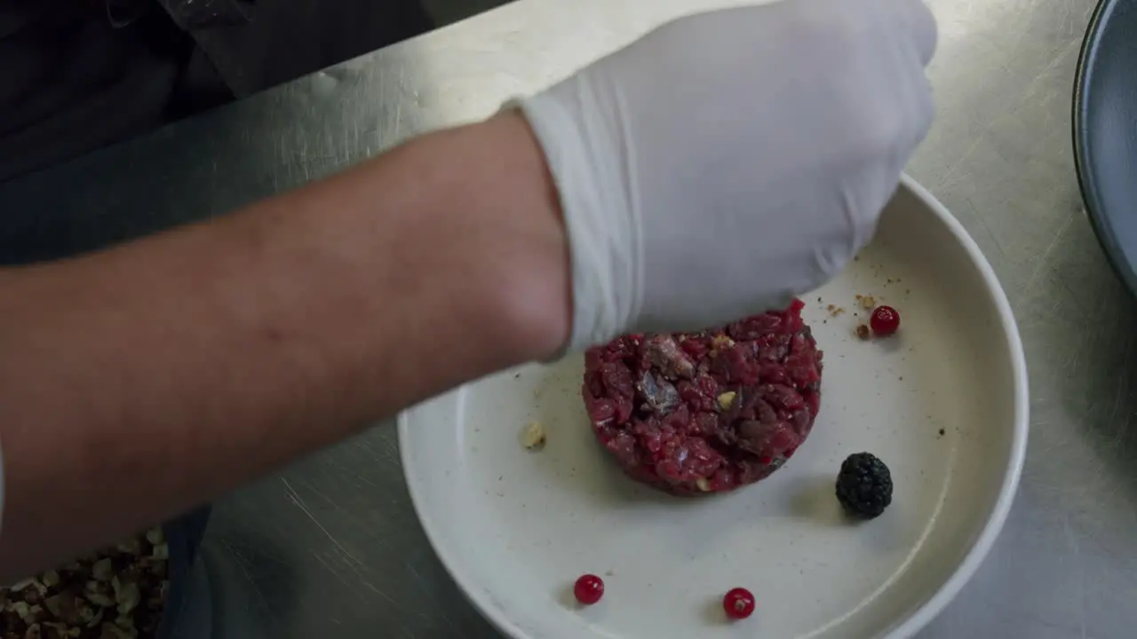 A professional Italian chef is preparing a plate of beef tartare in his kitchen