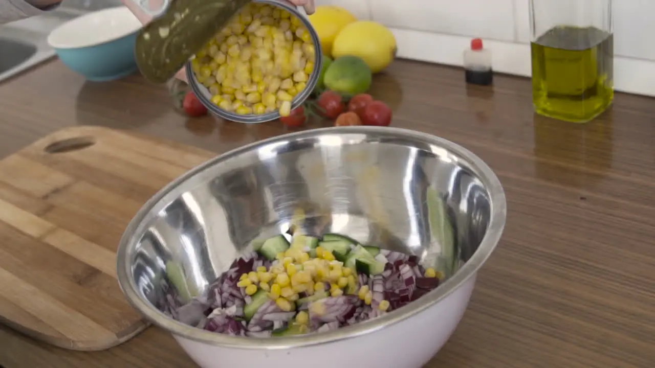 Slow motion as pouring boiled corn in a salad from a tin can